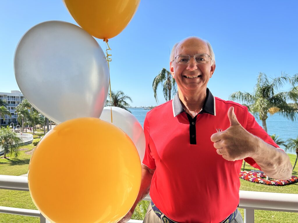 Smiling man outdoors, holding balloon bouquet